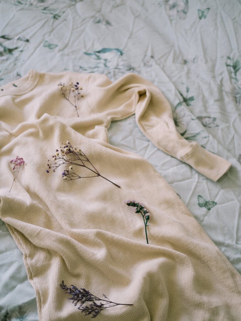 A soft beige dress with floral prints elegantly arranged on a floral-patterned bedspread.