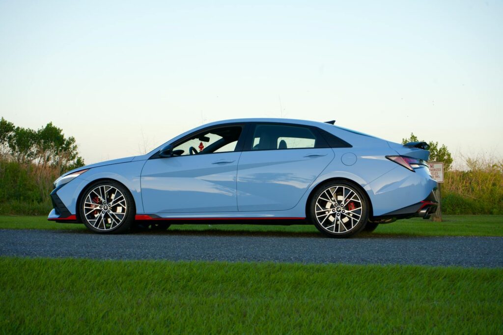 Side view of a blue Hyundai Elantra N parked on a road with grassy surroundings in Kissimmee, FL.