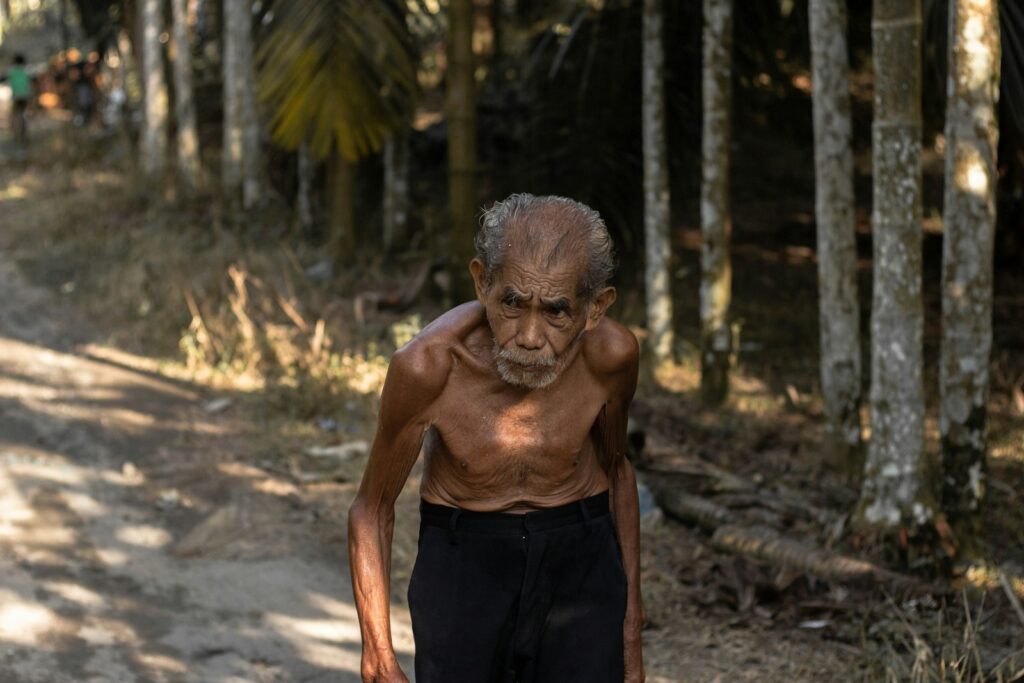 man standing while being surrounded by grey trees during daytime