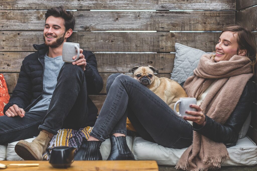 merry christmas, man, woman, dog, pet, pug, owners, couple, relationship, warm clothes, cozy, scarf, jackets, jeans, boots, fashion, people, happy, love, female, young, male, adult, caucasian, happiness, romantic, portrait, smile, smiling, girlfriend, date, boyfriend, together, animal, person, lovers, sitting, relaxing, rustic, cushions, couch, laughing, enjoying, coffee