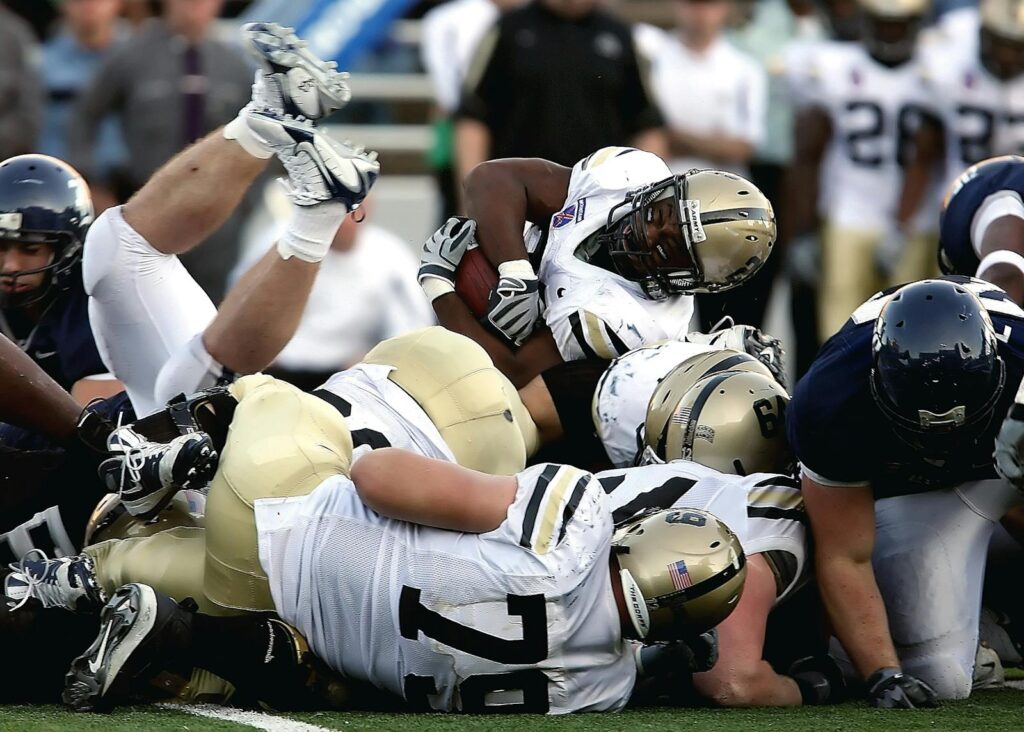 Intense action scene of football players tackling during a game, showcasing teamwork and sportsmanship.