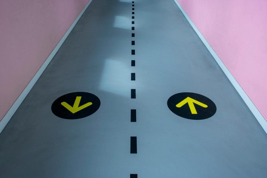A vibrant corridor featuring contrasting pink walls and directional arrows on the floor for visual guidance.