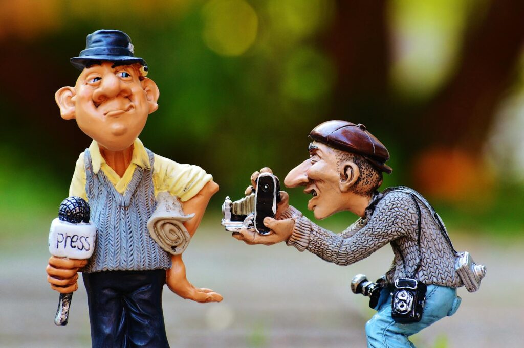 Charming figurines depicting press photographers capturing a moment.
