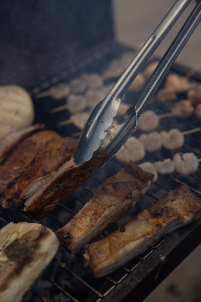 Close-up shot of ribs and skewers sizzling on an outdoor grill, creating a smoky barbecue atmosphere.