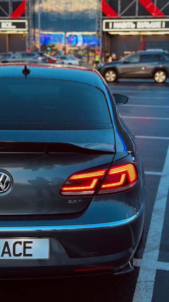 Rear view of a Volkswagen in an urban parking lot during twilight, showcasing sleek design and vibrant brake lights.