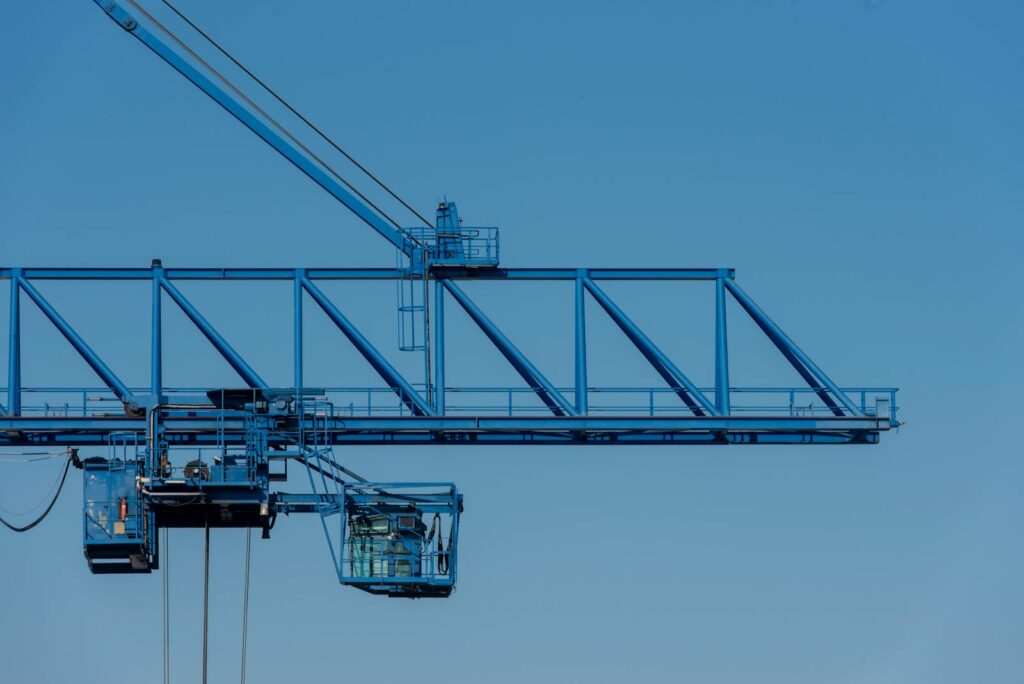 A blue industrial crane set against a clear sky, showcasing modern construction technology.