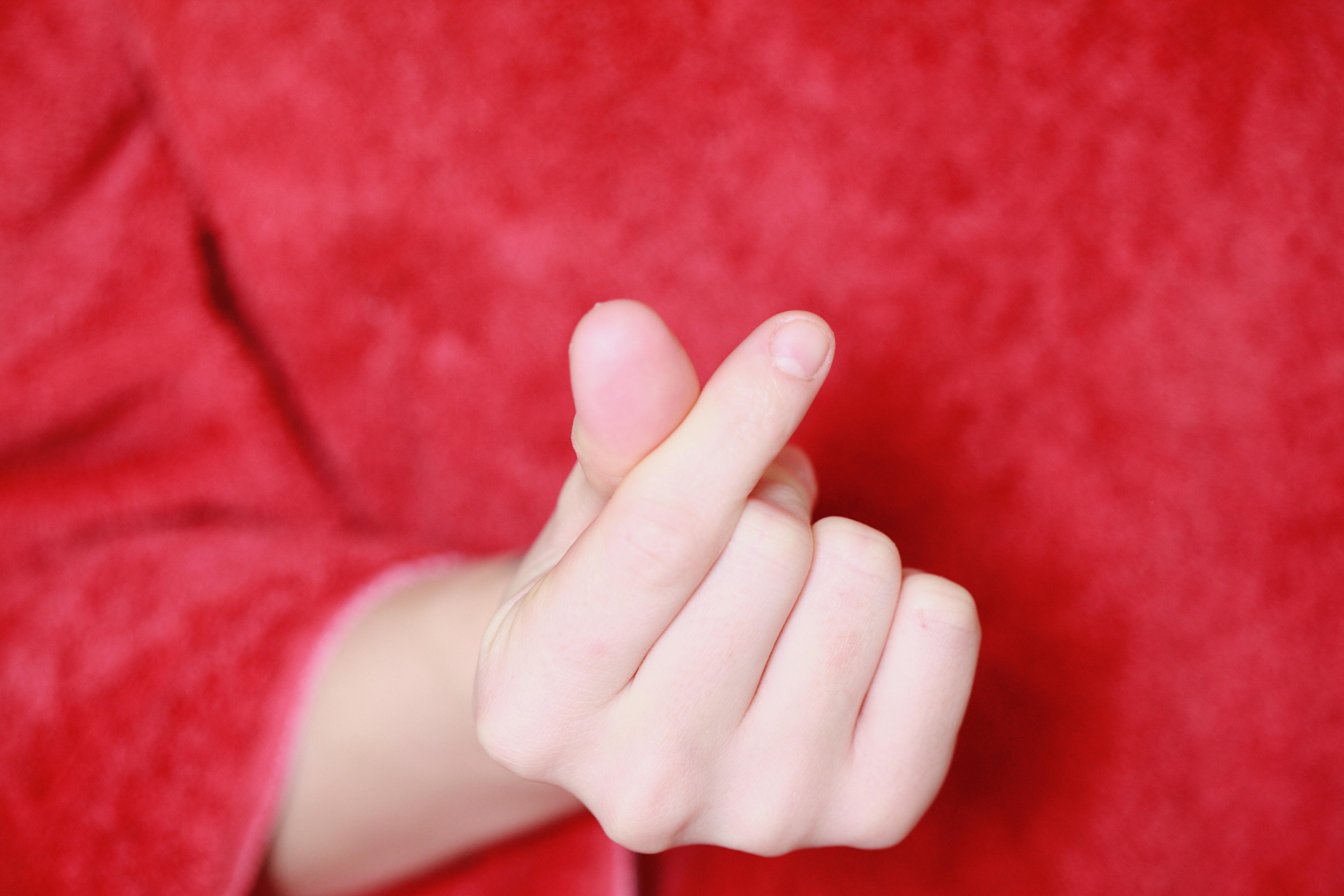Close-up of hand making a popular gesture on a red background.