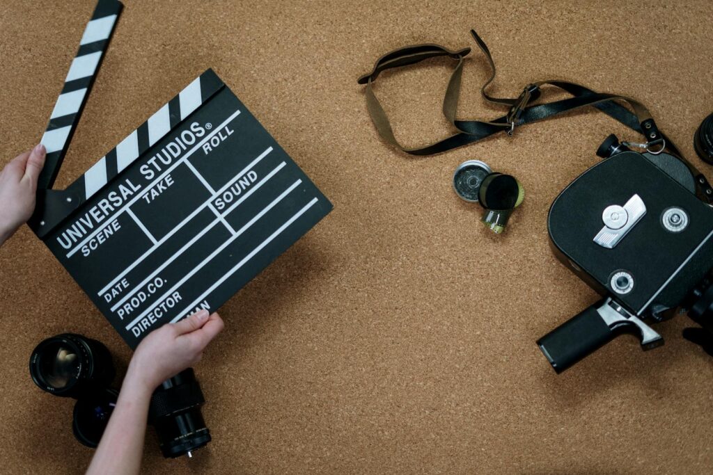 Top view of vintage film camera and clapperboard on cork background, evoking old cinema vibes.