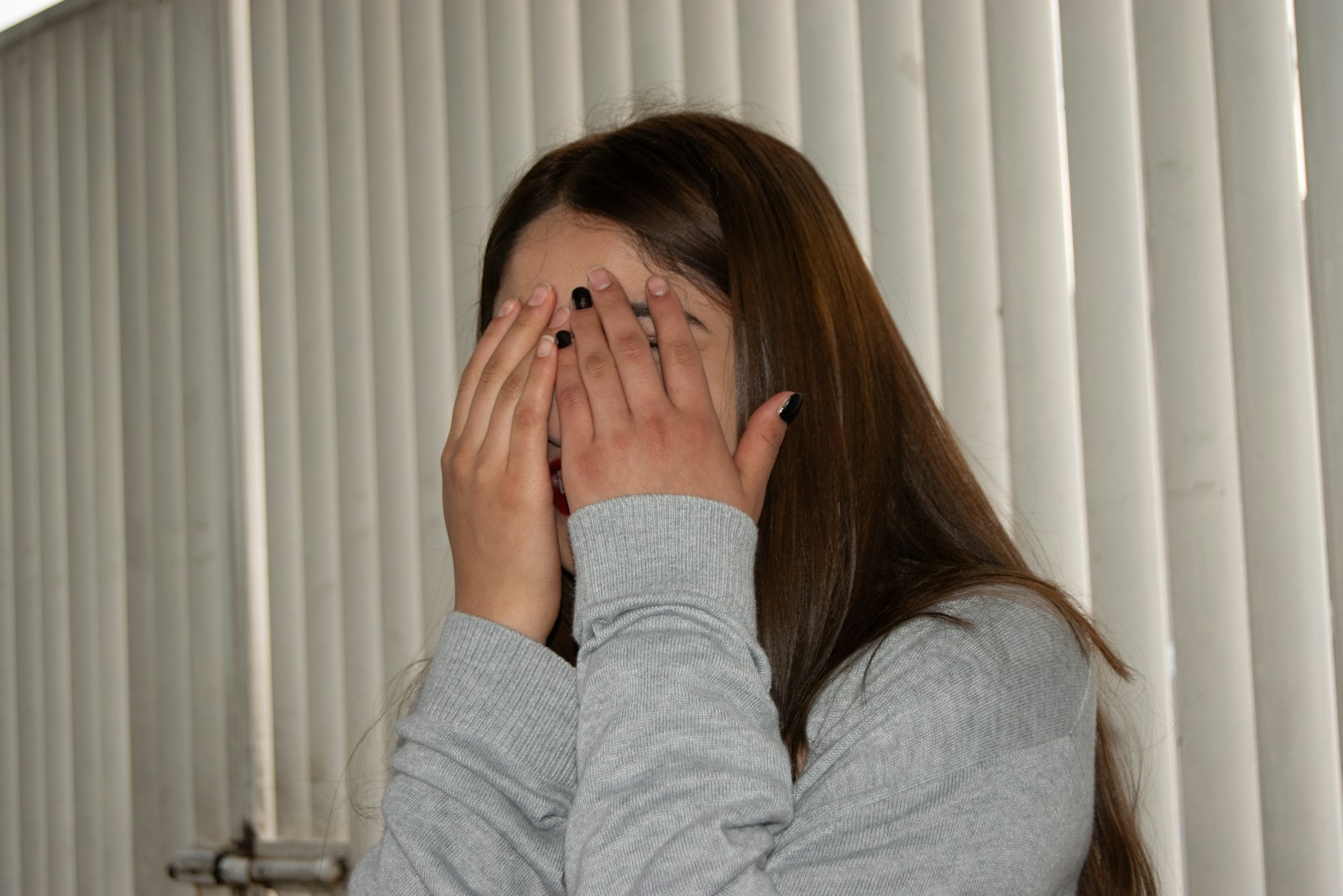 A woman covers her face with her hands