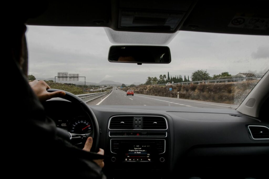 Anonymous man driving fast along asphalt road on modern vehicle in overcast weather