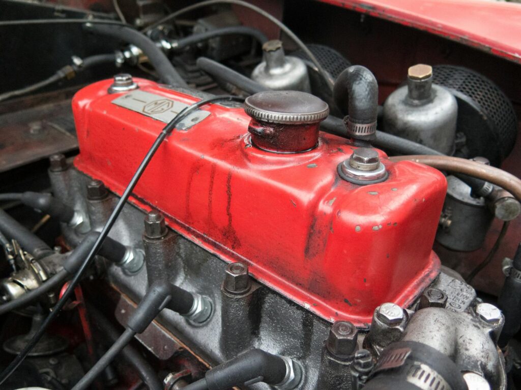 Detailed view of a classic red MG engine, highlighting its vintage mechanical components.