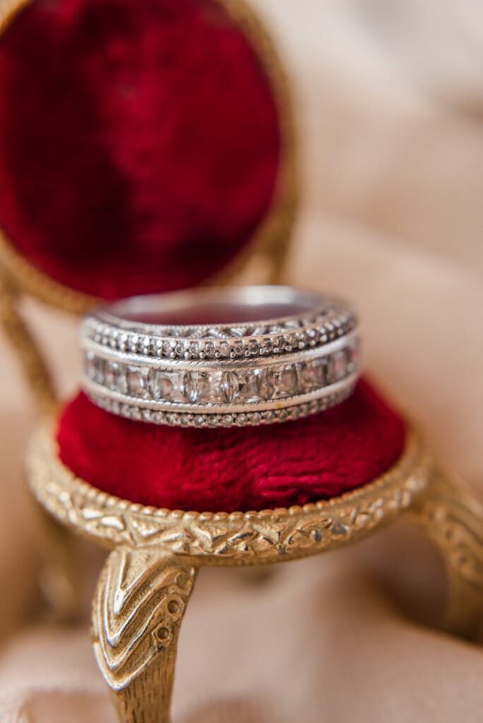 Close-up of a diamond ring on a small ornate red chair, showcasing luxury and elegance.