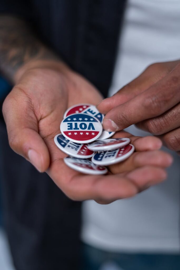 Close-up of hands holding patriotic voting pins representing democracy.