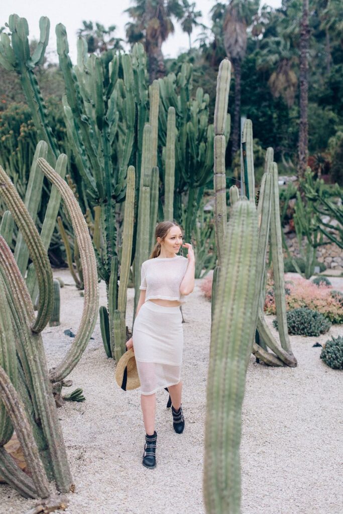 Woman in white outfit strolling through cactus garden in Barcelona's scenic landscape.