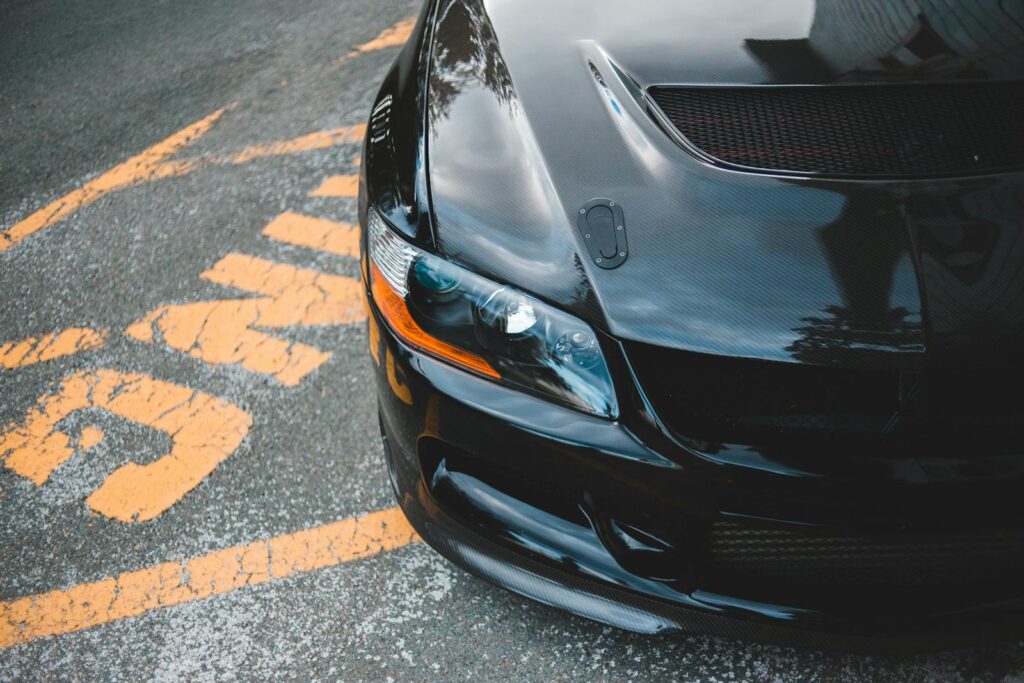 Black car with sporty design parked on marked city street with reflections.