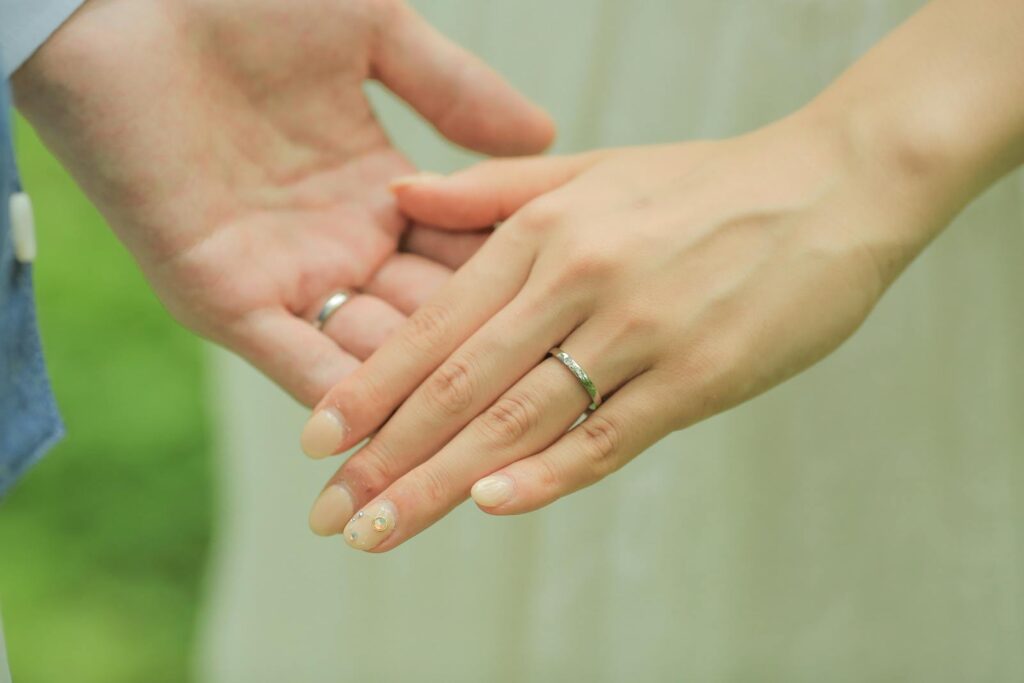 Close-up of newlywed couple's hands showcasing wedding rings in an intimate moment.