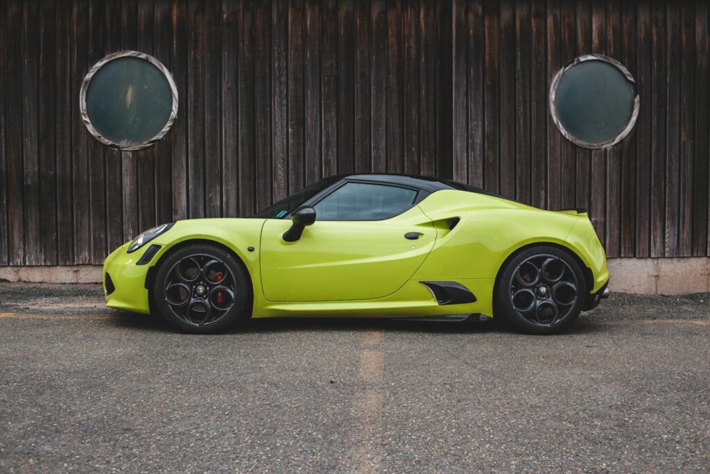 Bright yellow luxury sports car parked by a wooden fence.
