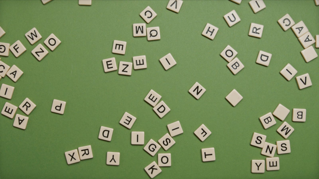 Scattered alphabet tiles on a green background, perfect for word games and educational themes.