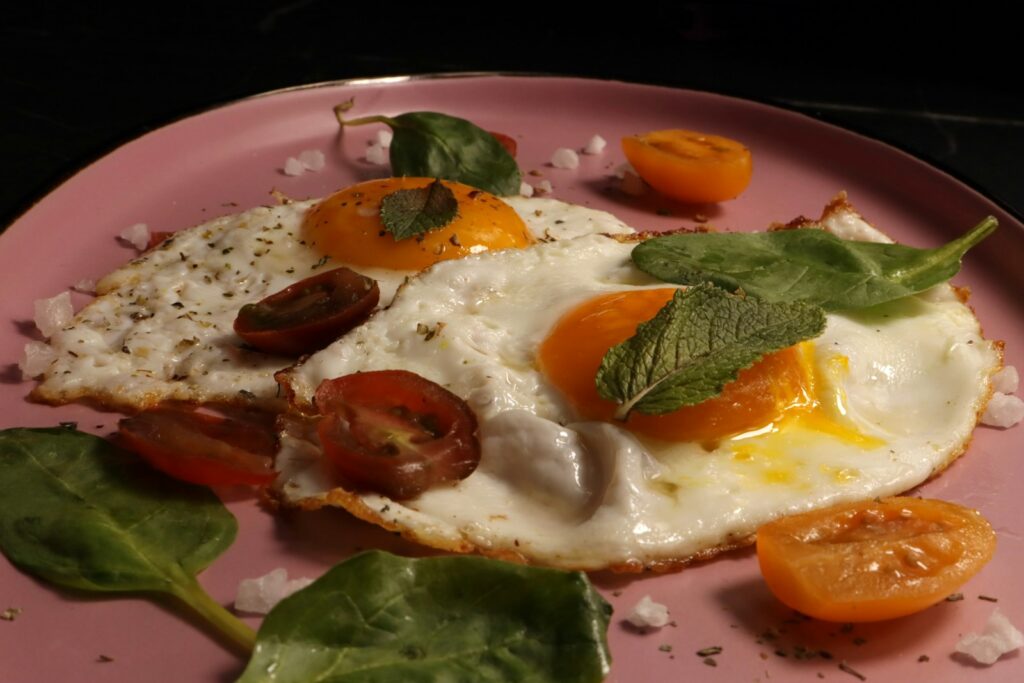 Fried eggs are served with tomatoes and herbs.