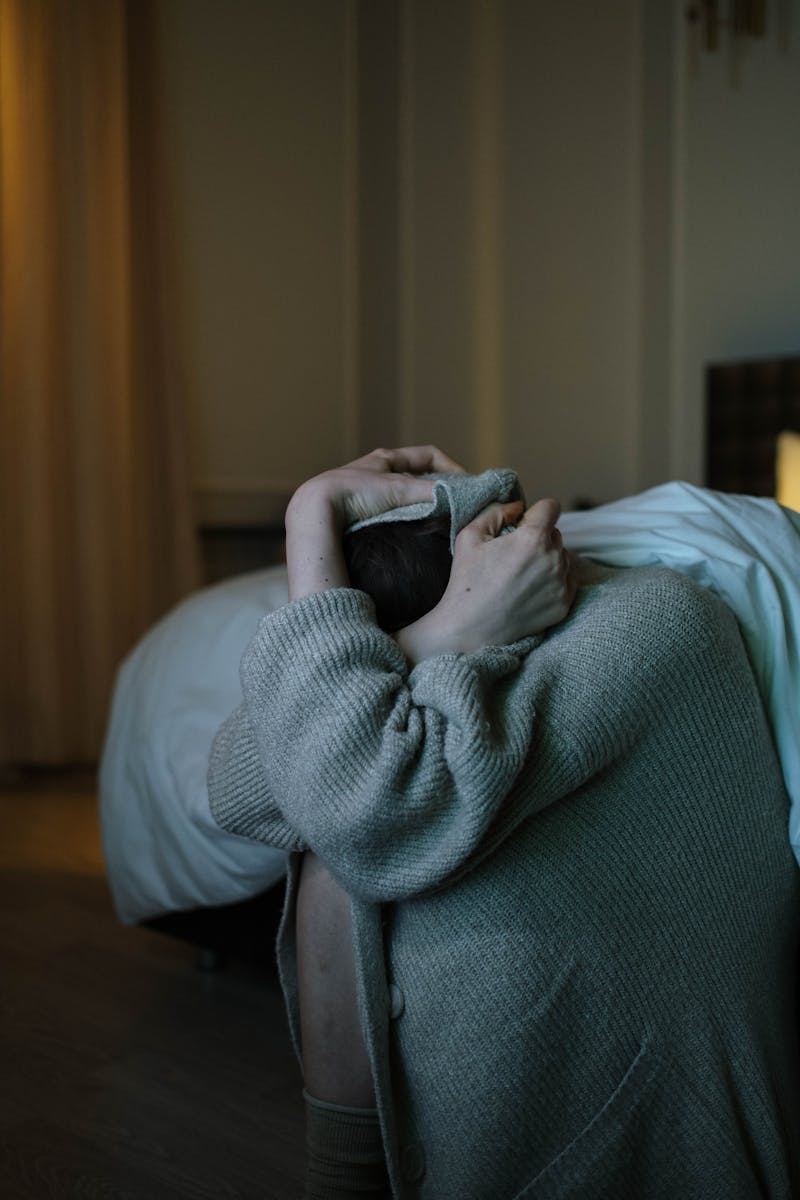 A person wrapped in a blanket, reflecting anxiety and stress in a dimly lit room.