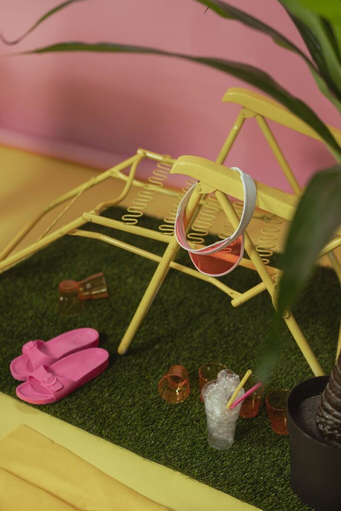Vibrant garden scene with a yellow deck chair, plastic cups, and pink slippers.