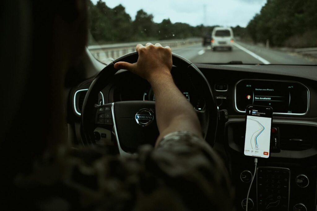 A driver navigates the highway with a smartphone GPS, showcasing modern car interior design.