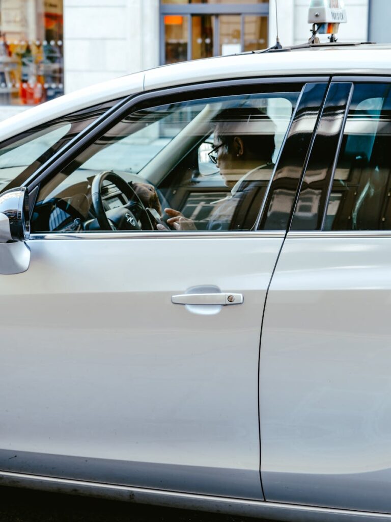 Side view of a man using a smartphone inside a car, showcasing distracted driving.