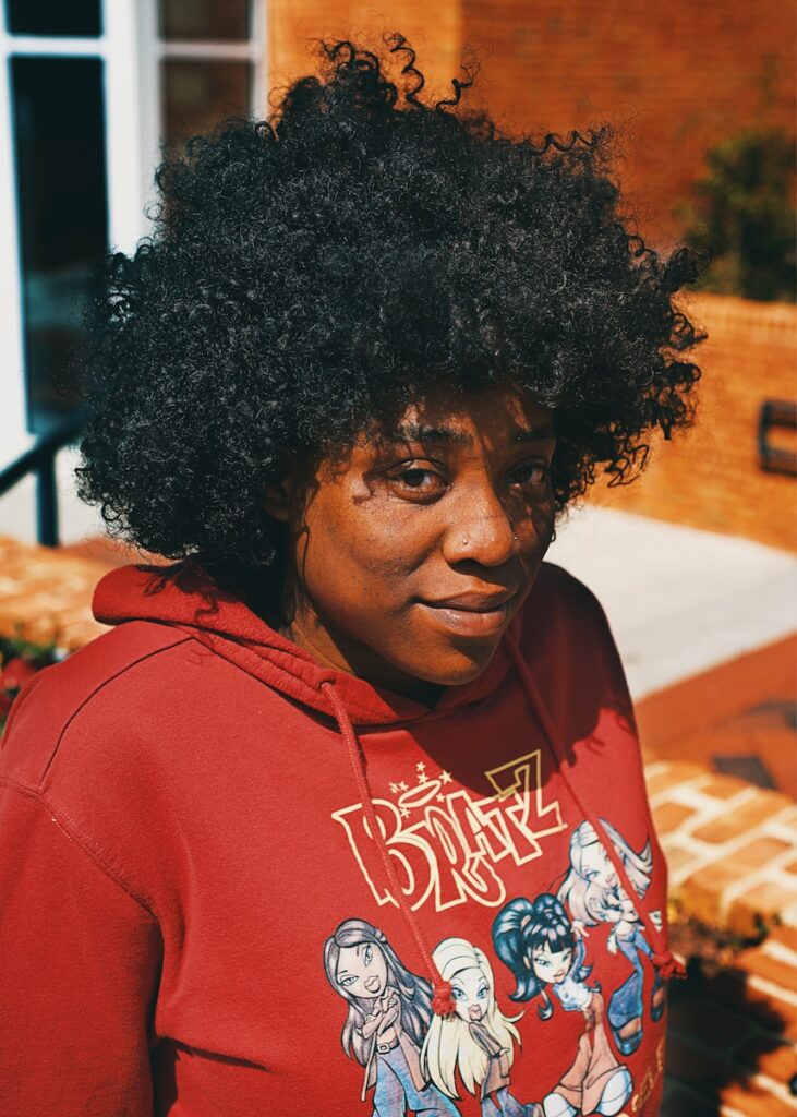 A person in a red hoodie is looking at the camera.