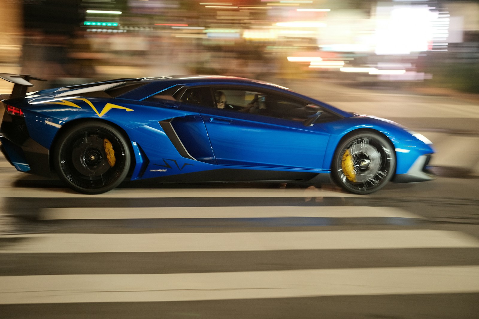 A blue sports car driving down a city street