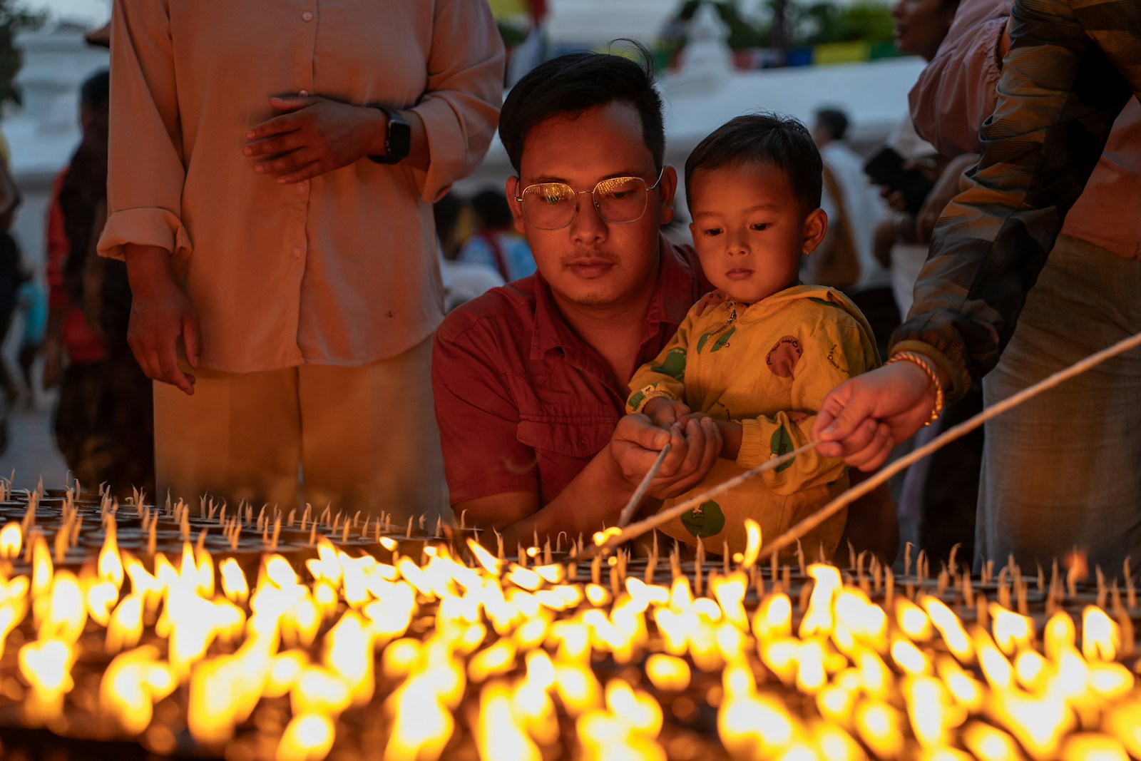 A group of people standing around a cake with candles on it