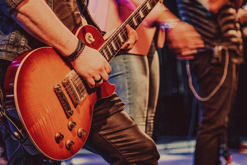 man in black suit playing brown electric guitar