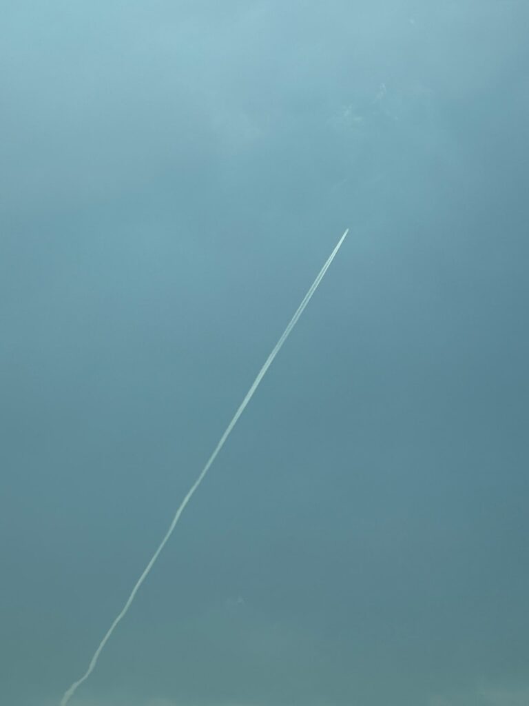 An airplane is flying in the sky with a contrail