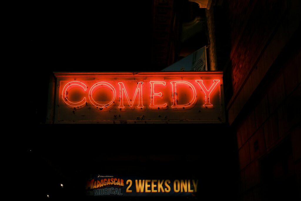 a neon sign that says comedy on the side of a building