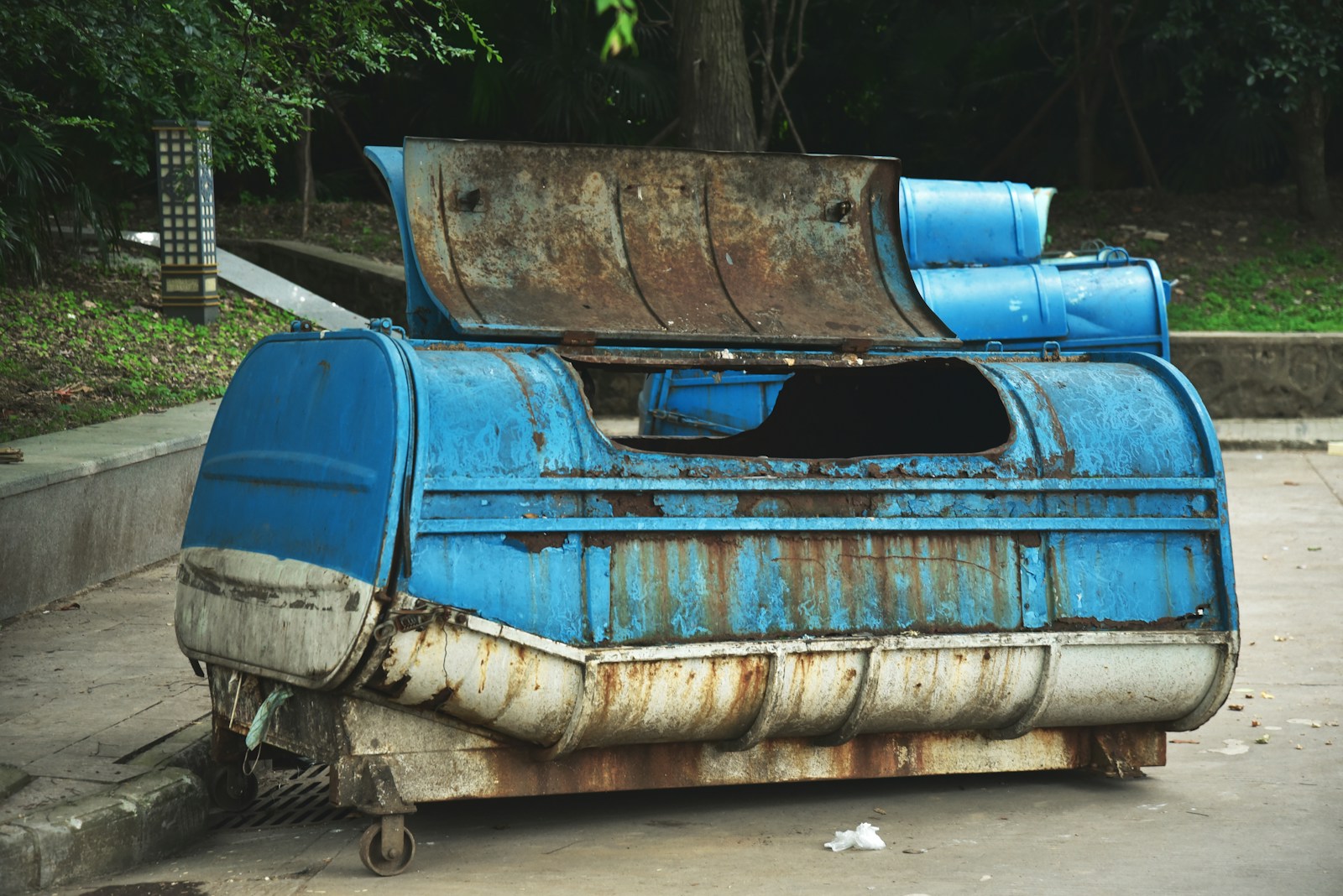 a rusted out blue and white boat sitting on top of a sidewalk