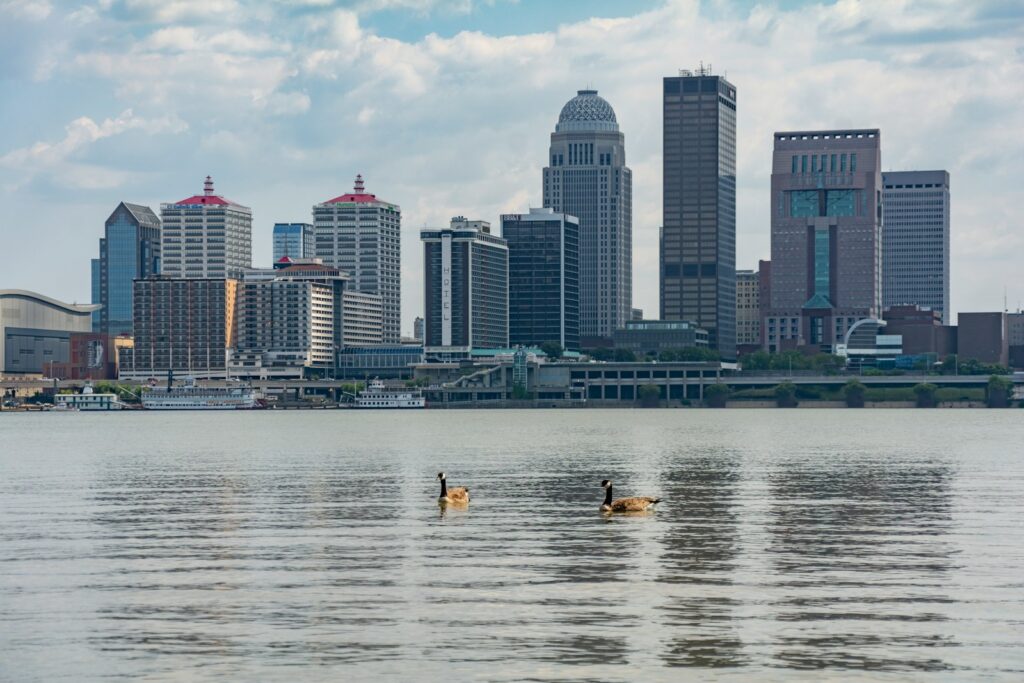The louisville skyline is seen over the river.