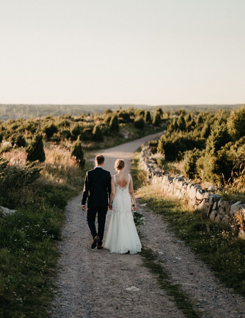A bride and groom walking down a dirt road