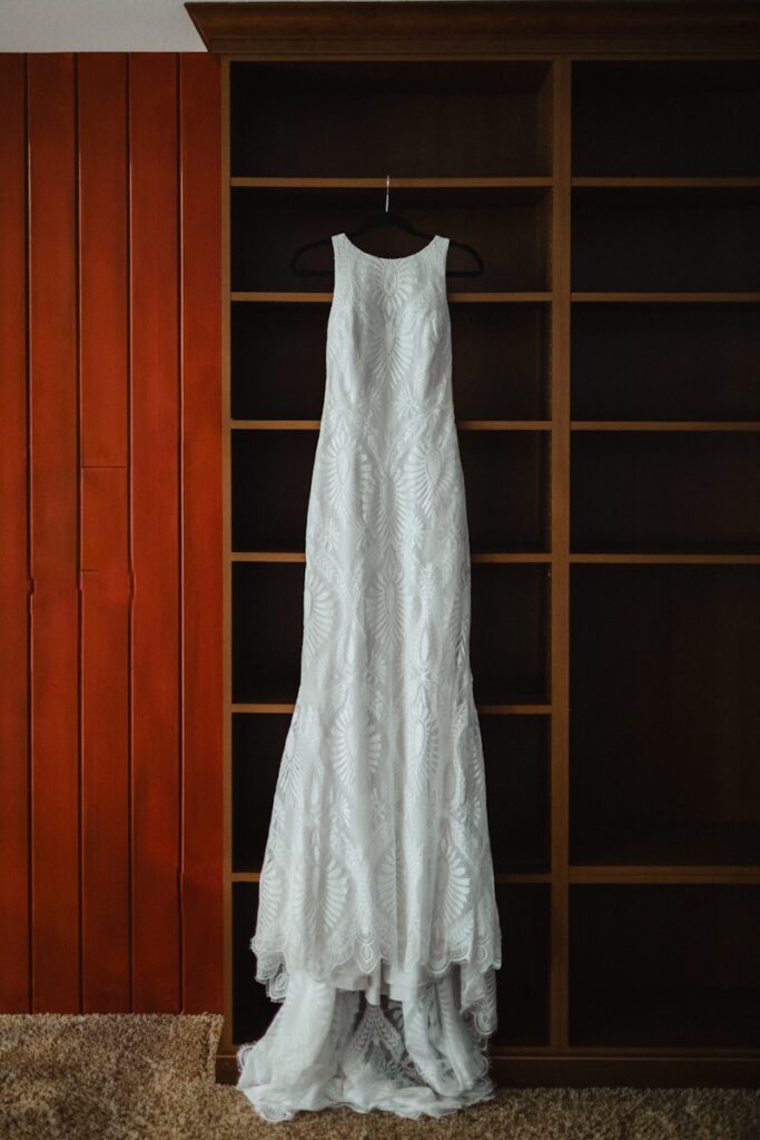 a wedding dress hanging in front of a bookcase