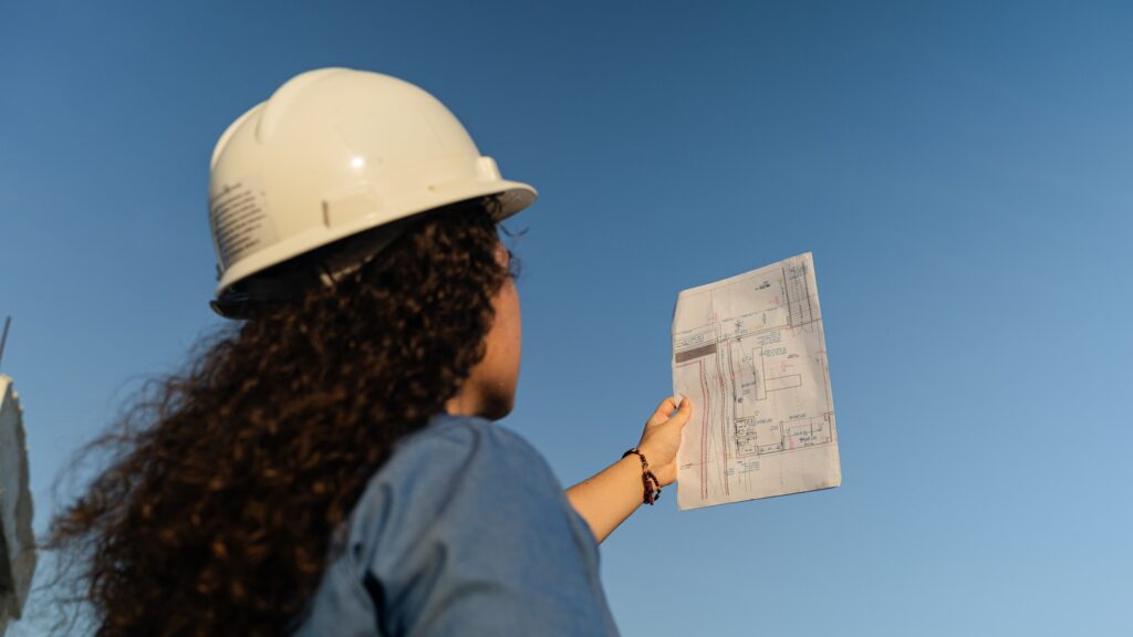 a woman wearing a hard hat holding a piece of paper