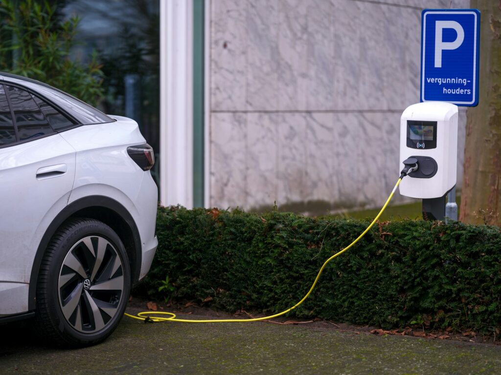 A white electric car plugged in to a parking meter