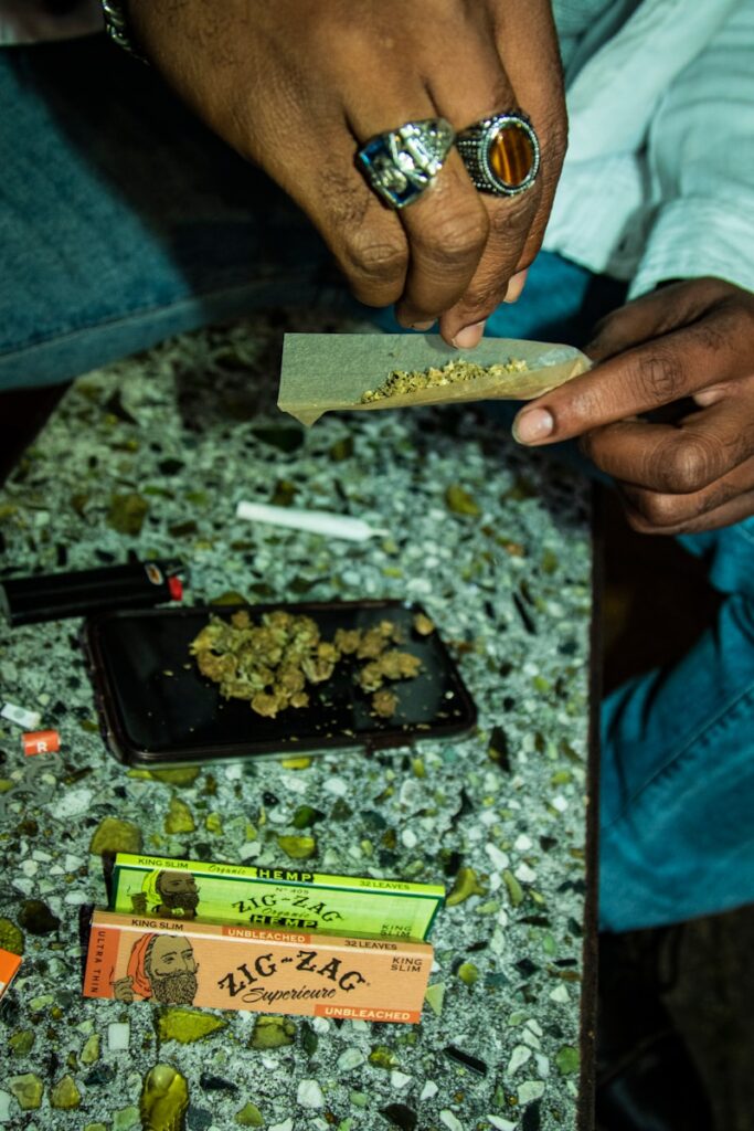 person holding brown wooden board with cigarette butts