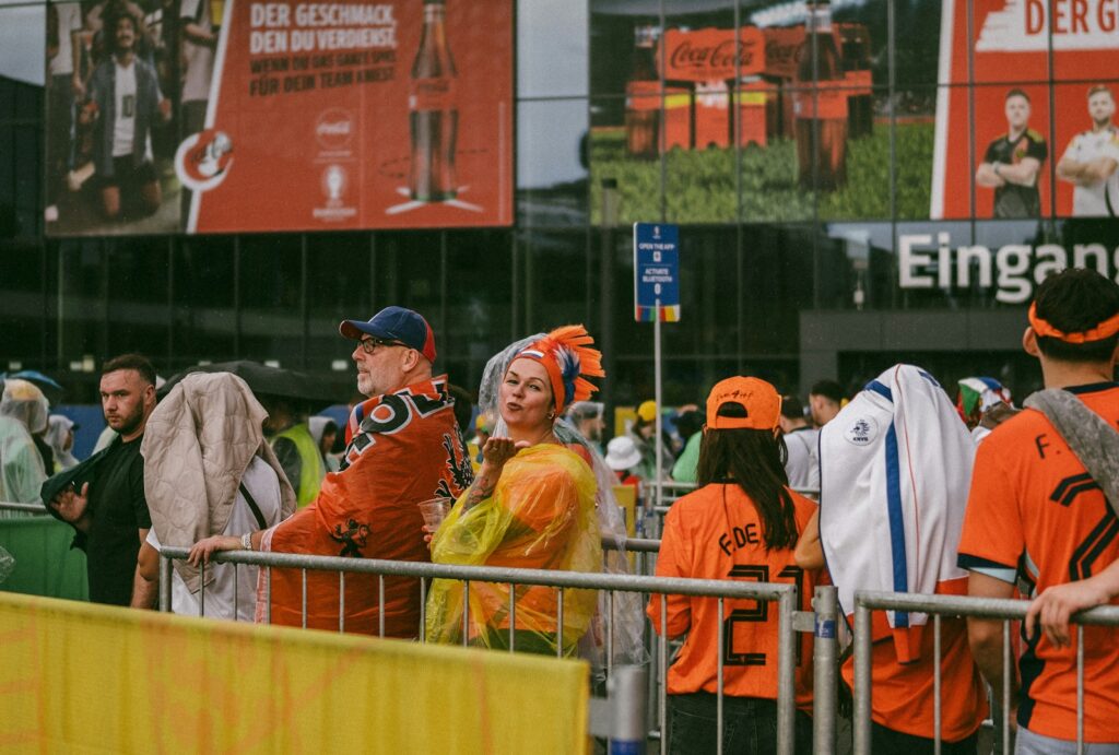 A group of people in orange shirts standing in front of a fence