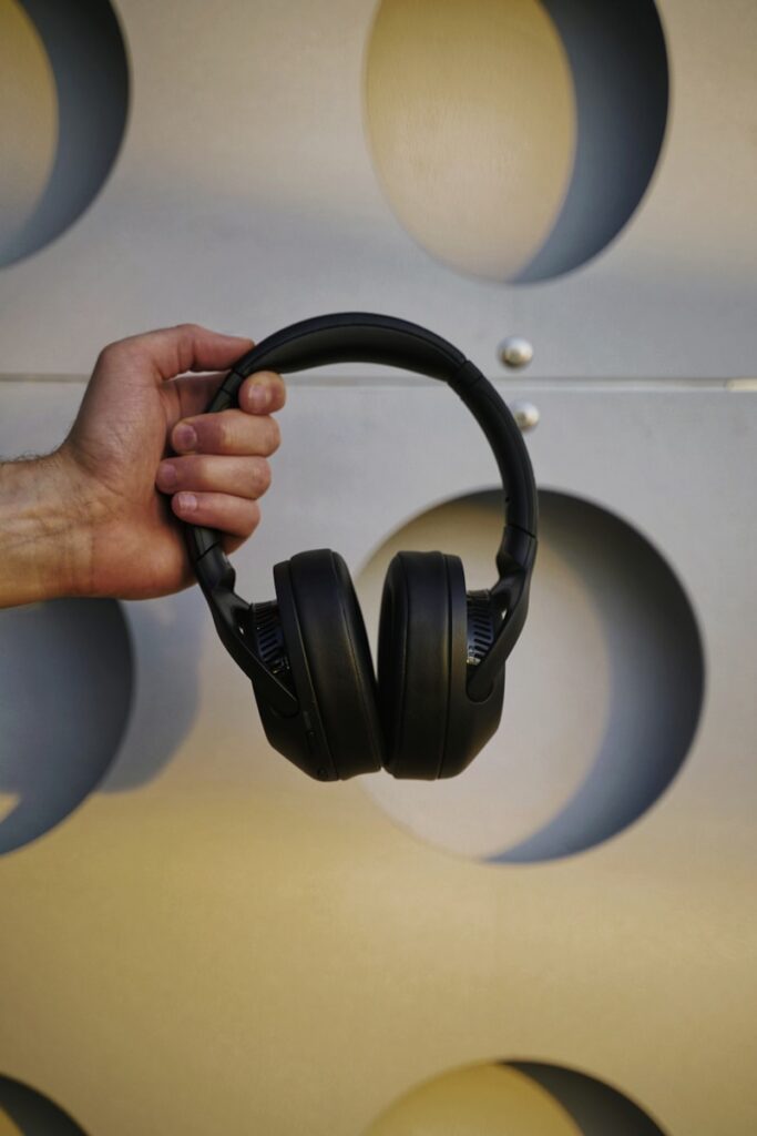 a hand holding a pair of black headphones