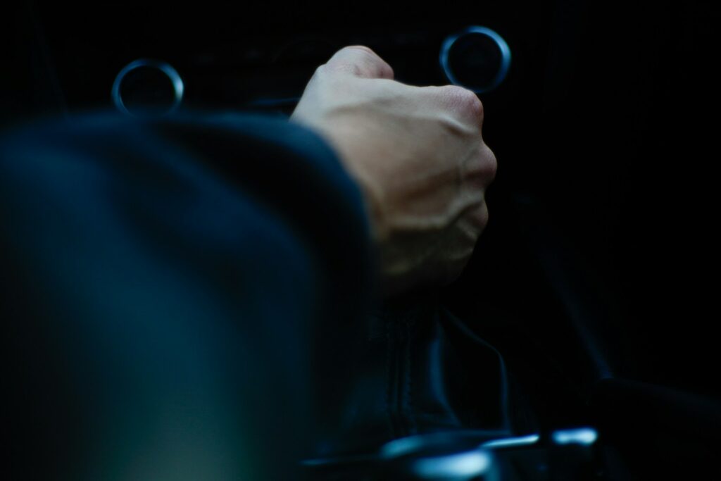 A person driving a car with their hand on the steering wheel