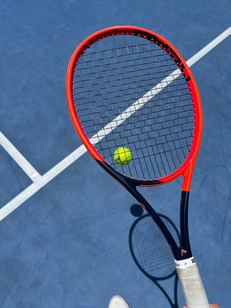 Tennis racket holding a tennis ball on the court.