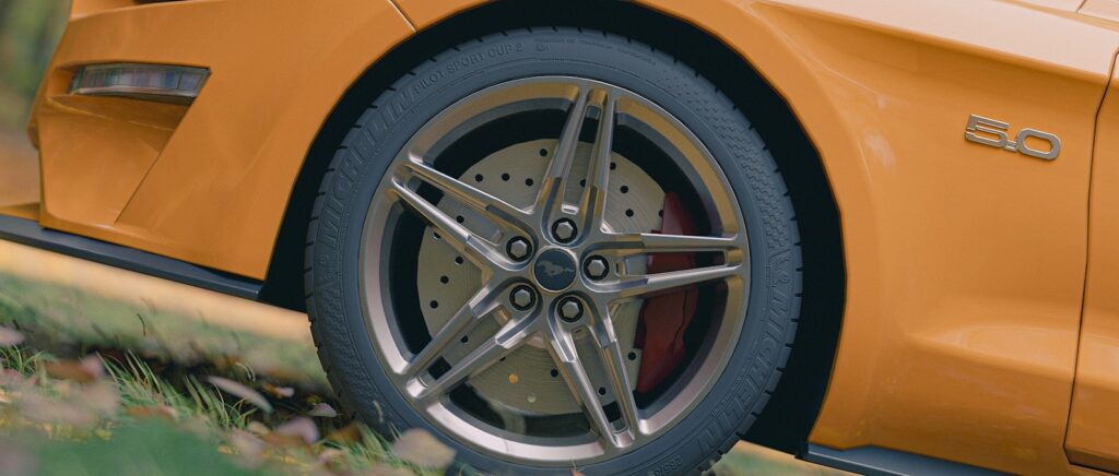 Here is a caption for the image: a yellow sports car's wheel.