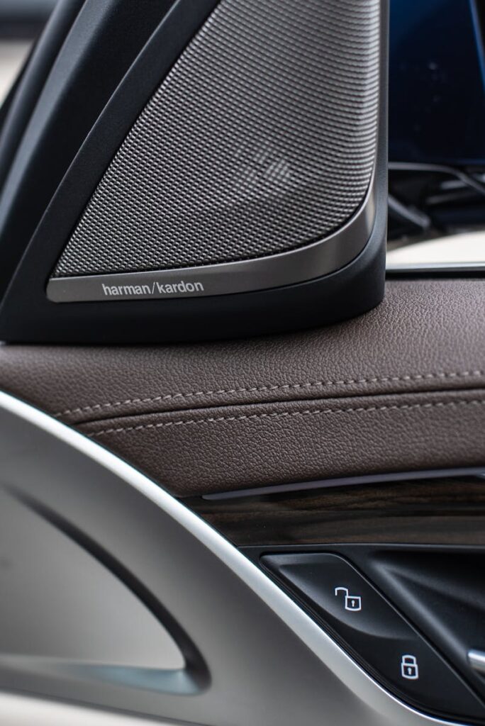 Detailed view of a Harman Kardon speaker and car control buttons inside a luxury vehicle.