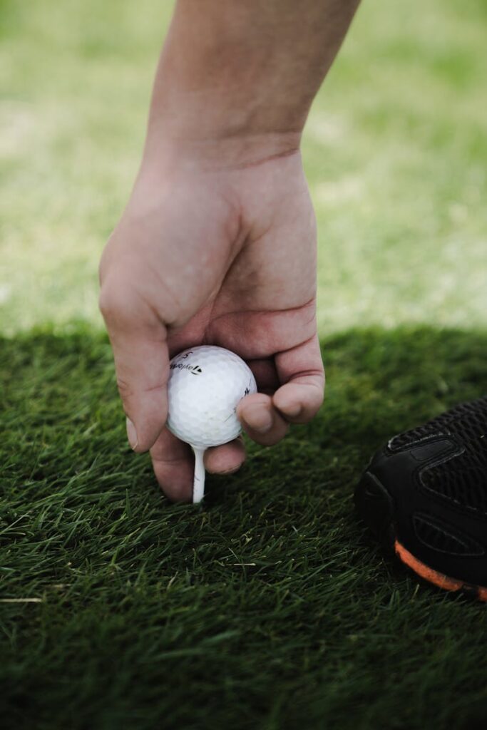 A person carefully placing a golf ball on a tee, ready for a perfect shot.