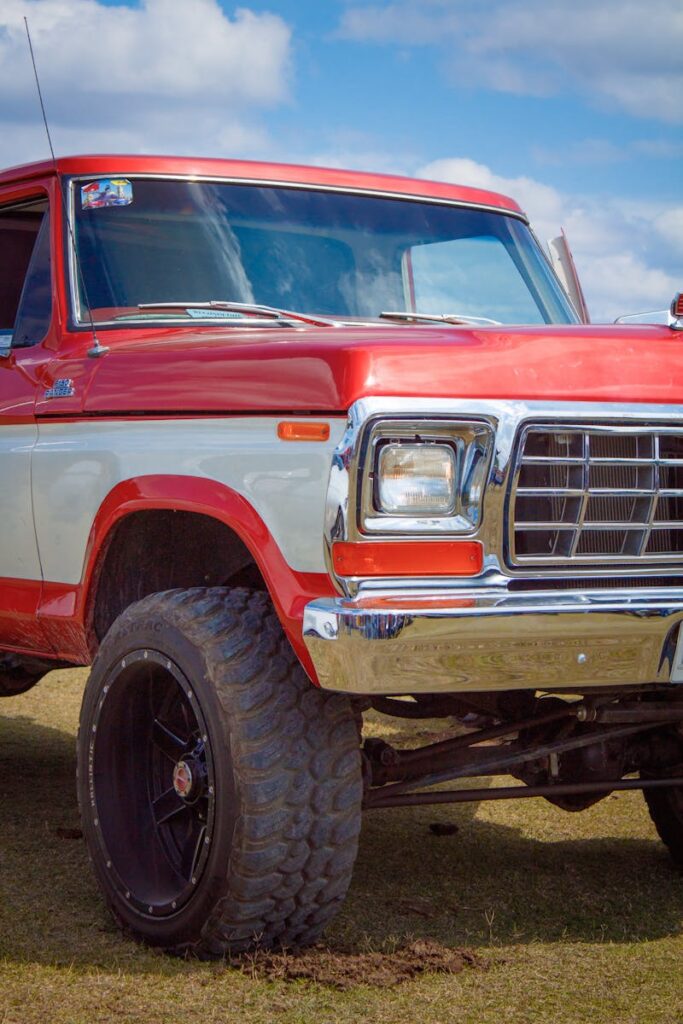 Classic red and white Ford F-250 Ranger with suspension lift under a blue sky.