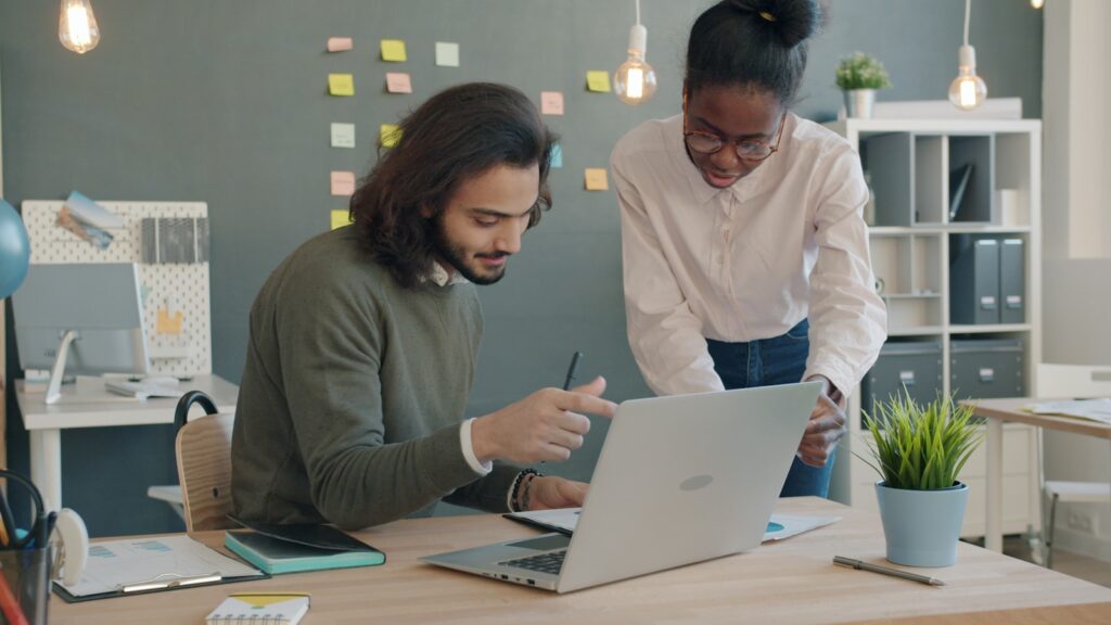Two colleagues collaborating on a laptop in an office.