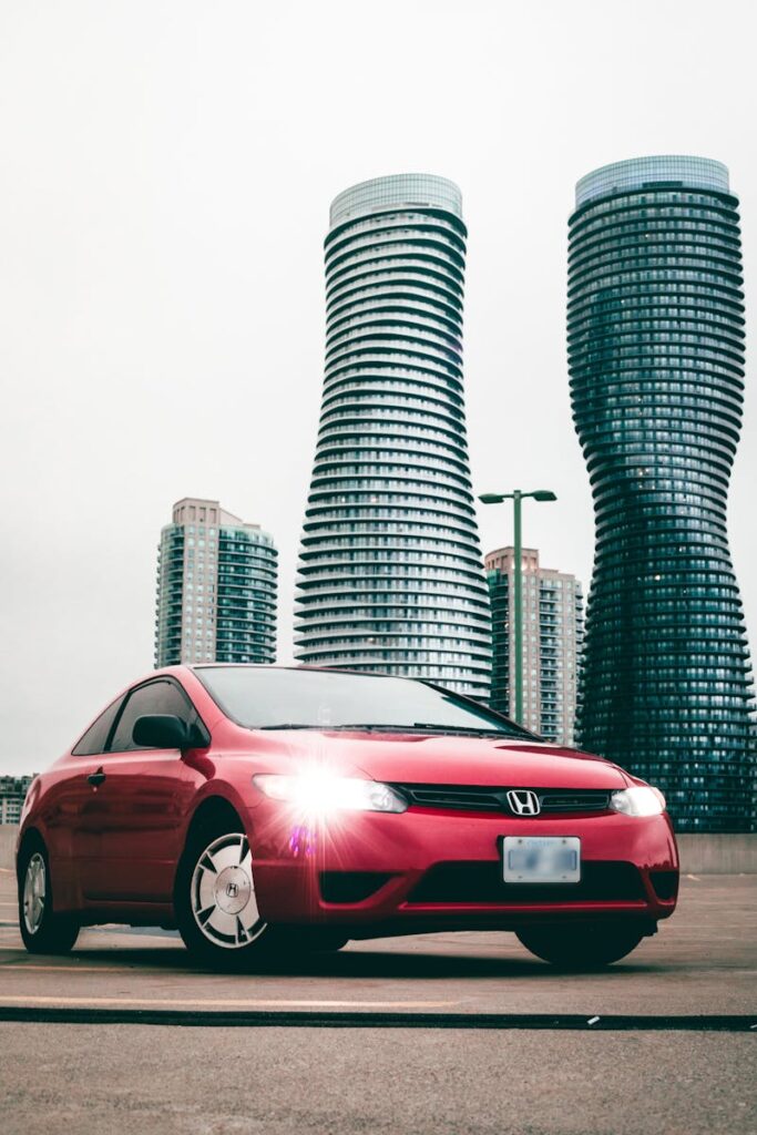 Red Honda car parked in front of distinctive twisted towers in Mississauga, Canada.